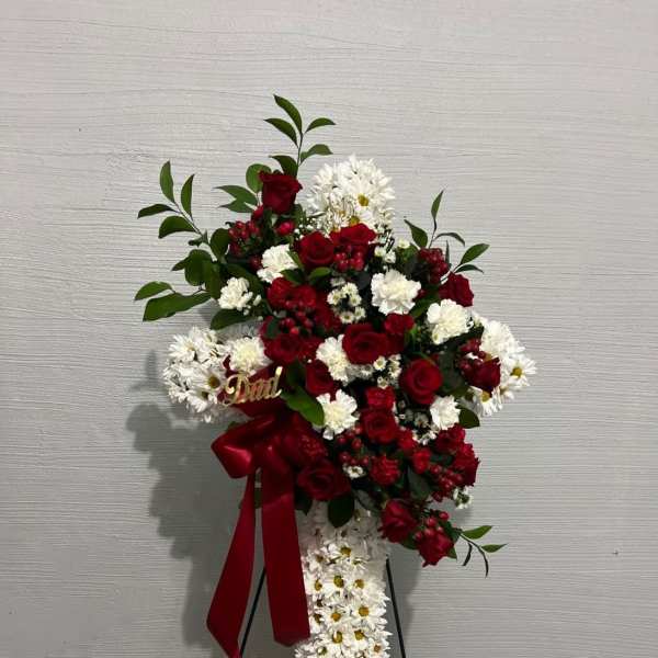 Standing floral spray with red roses and white daisies on a black easel