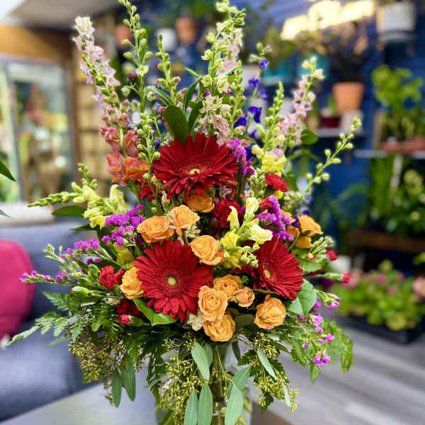 Mixed bouquet with red gerbera daisies and orange roses in a glass vase