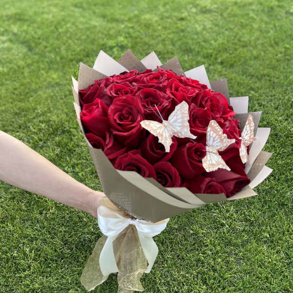 Bouquet of red roses wrapped in beige paper with butterfly accents
