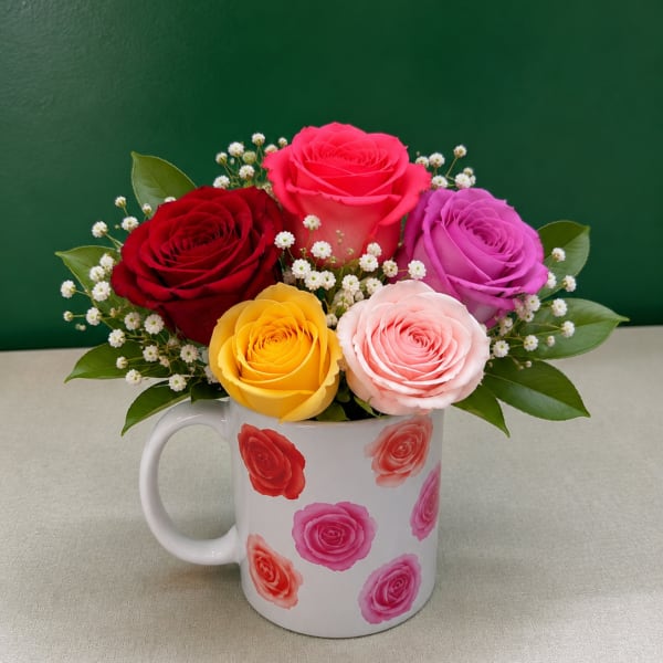 Colorful roses arranged in a white mug with small white filler flowers