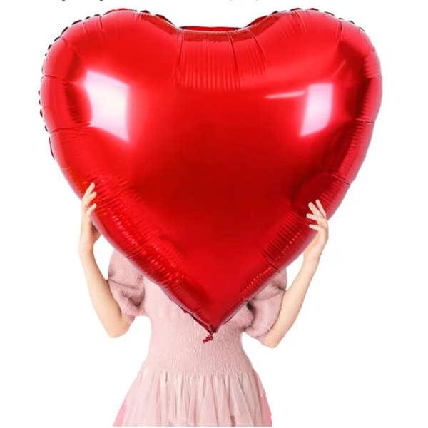 Person holding a large red heart-shaped balloon