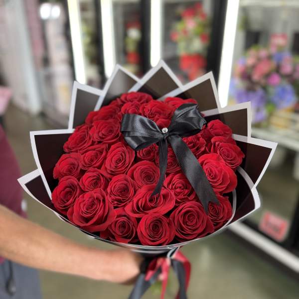 Bouquet of red roses wrapped in black paper with a black ribbon