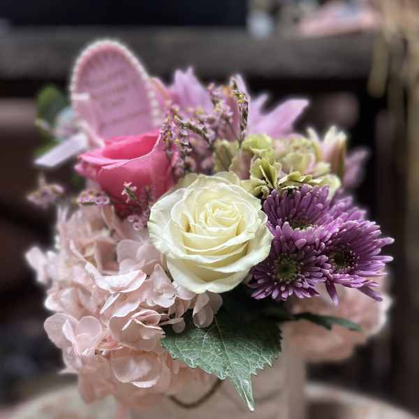 Pink and white bouquet with roses, hydrangea, and purple daisies in a gift bag