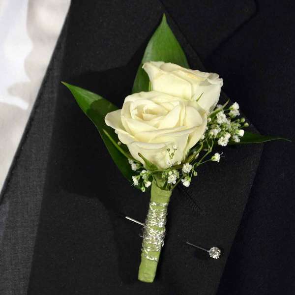 White rose boutonniere with baby's breath on a black suit lapel