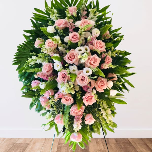 Large standing spray of pink roses and white flowers with tropical greenery