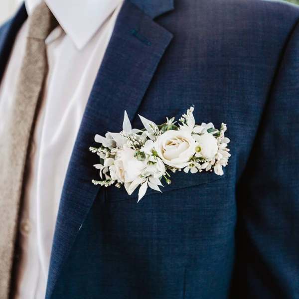 White floral boutonniere pinned to a navy suit jacket