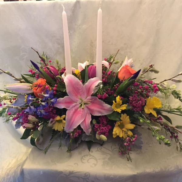 Pink lily centerpiece with two white taper candles