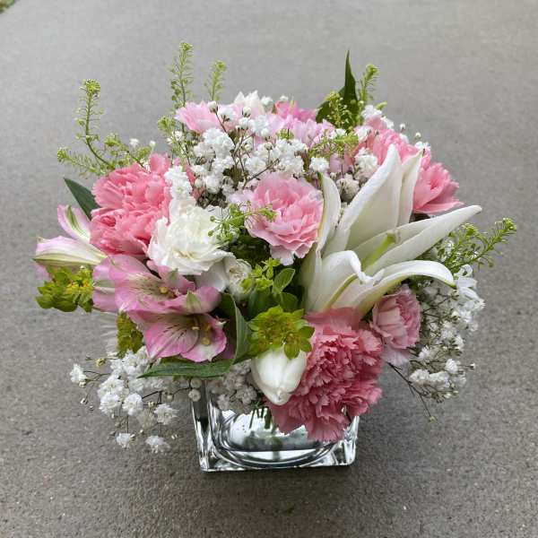 Pink and white floral arrangement in a square glass vase