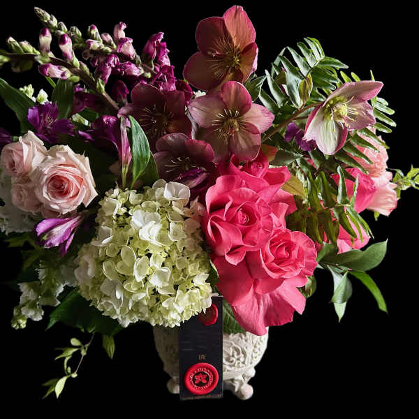 Mixed bouquet of pink roses, hydrangeas, and hellebores in a decorative vase
