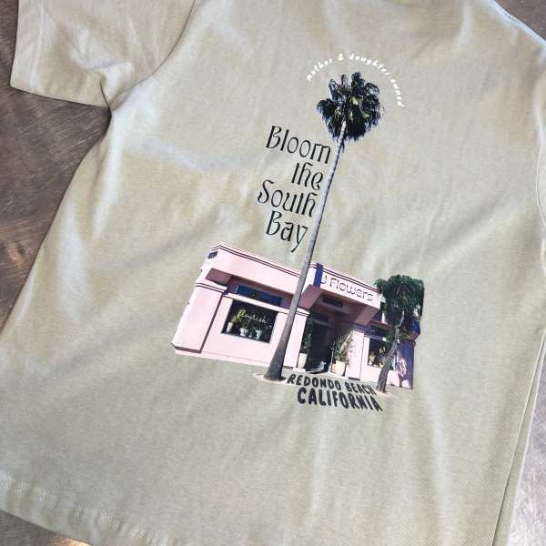 Light green T-shirt with a floral shop graphic and palm tree print