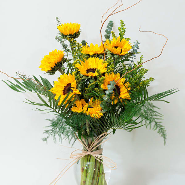 Sunflower arrangement in a clear glass vase with airy greenery