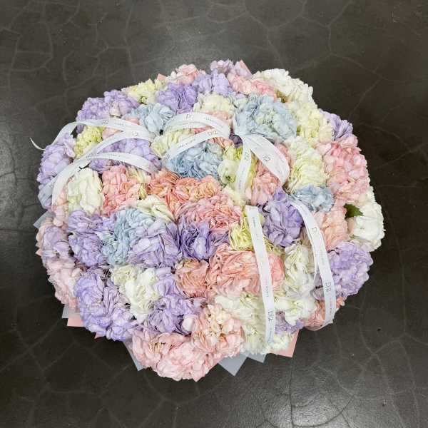 Pastel hydrangea bouquet with ribbon ties on a dark floor