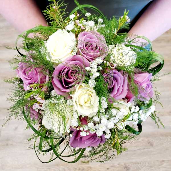 Handheld bouquet of purple and white roses with airy filler flowers