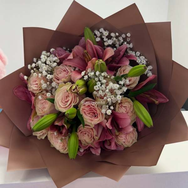 Bouquet of pink roses and lilies wrapped in brown paper