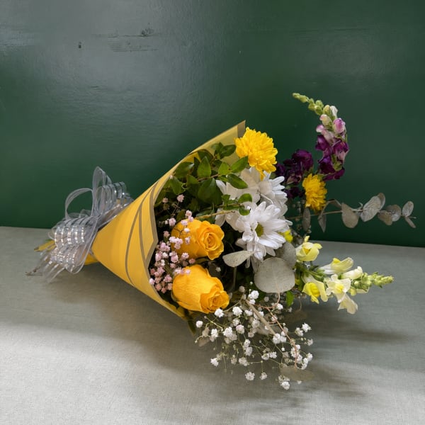 Bouquet of yellow, white, and purple flowers wrapped in yellow paper