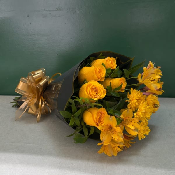 Yellow roses and yellow flowers wrapped in black paper with a gold bow