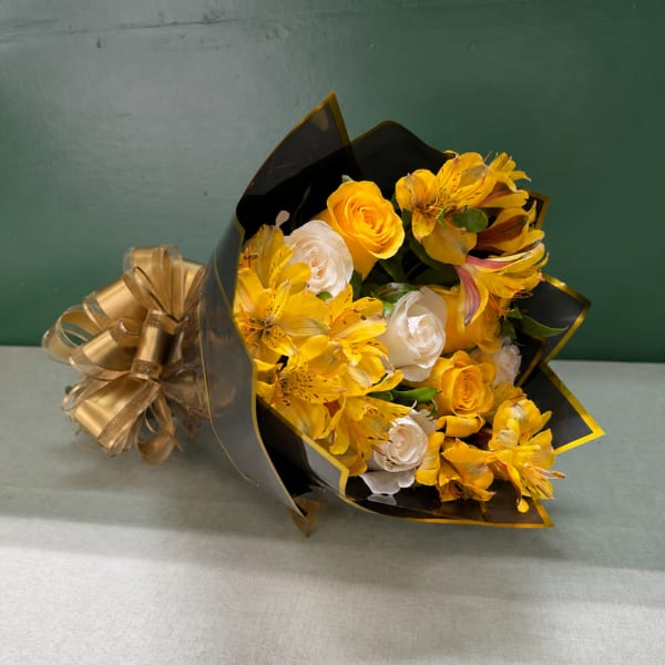 Yellow and white bouquet wrapped in black paper with a gold ribbon