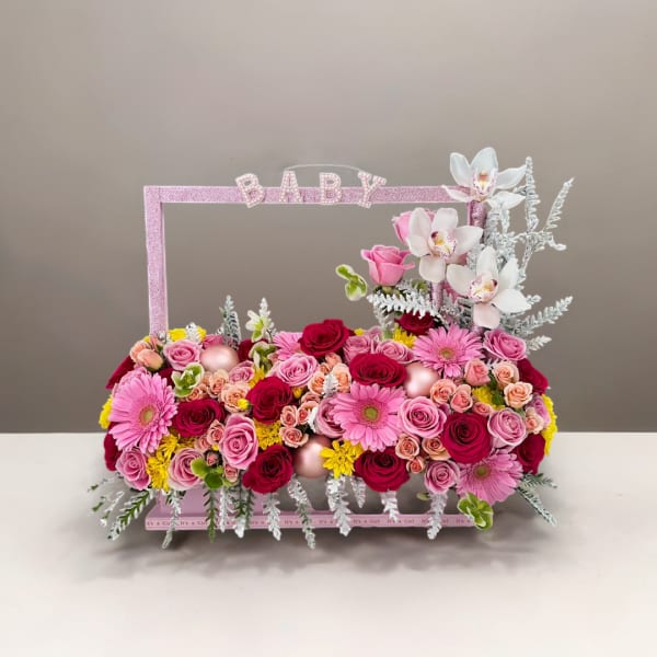 Pink and white floral baby gift arrangement with roses and orchids