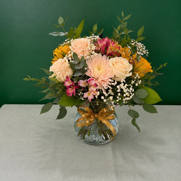 Mixed bouquet of roses, daisies, and pink flowers in a glass vase