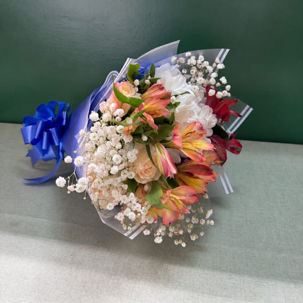 Bouquet of pink and white flowers wrapped in blue paper with a ribbon