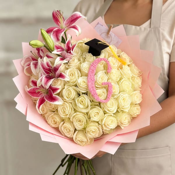Bouquet of cream roses and pink lilies with a graduation cap topper
