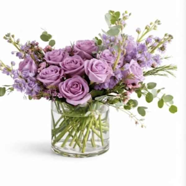 Lavender roses and purple flowers in a clear glass vase