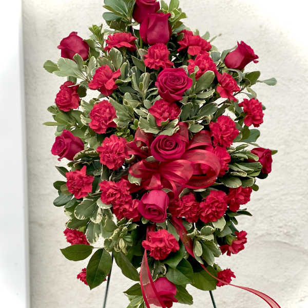Standing floral spray with red roses and carnations on an easel