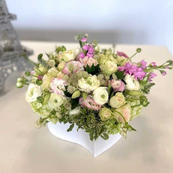 Pastel bouquet of roses and ranunculus in a white vase