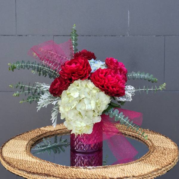 Bouquet of red and white flowers in a pink glass vase