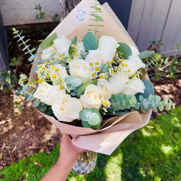 Bouquet of white roses and small daisies with eucalyptus in paper wrap