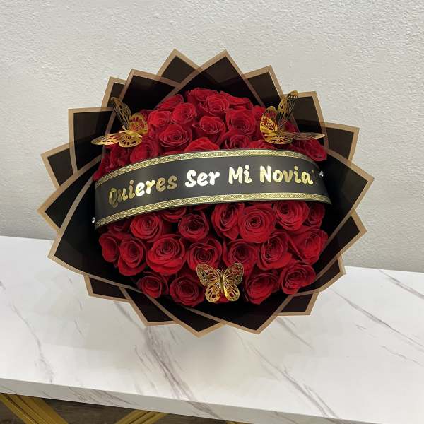 Red rose bouquet with a black and gold "Quieres Ser Mi Novia" banner