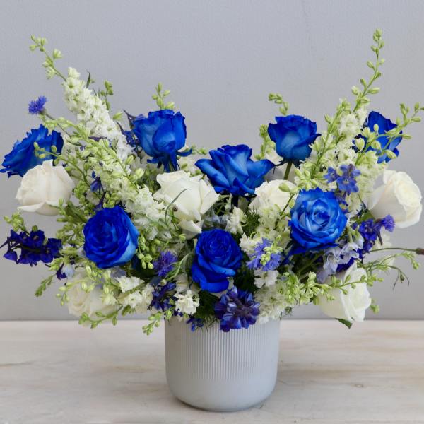 Blue and white flower arrangement in a white ceramic vase