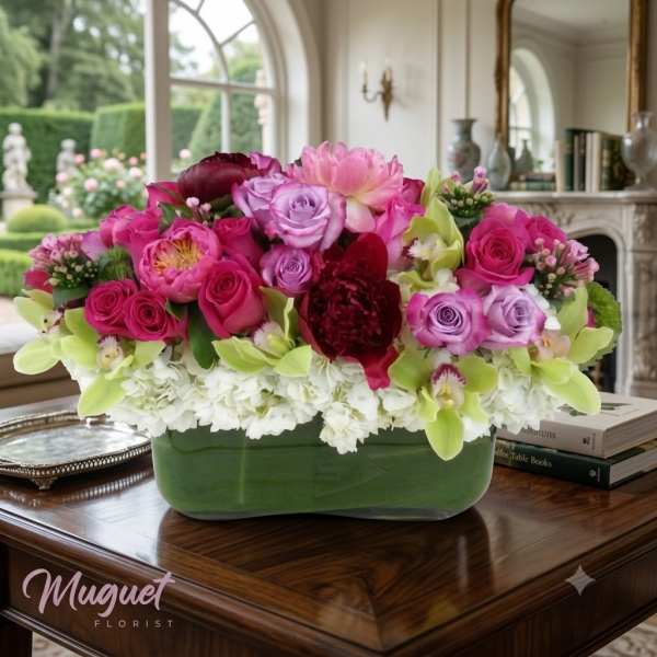 Pink and lavender roses arranged in a green rectangular vase