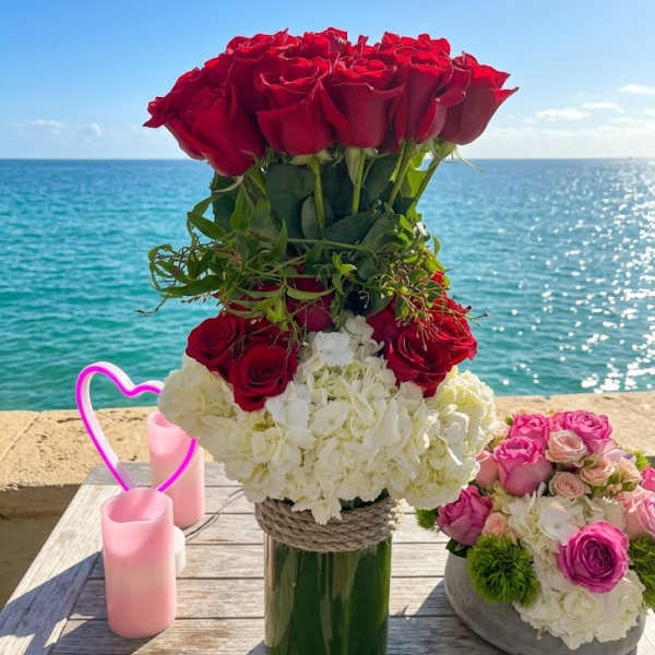 Red rose arrangement in a glass vase with white hydrangeas and pink roses
