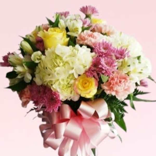 Bouquet of mixed pastel flowers with a pink ribbon in a glass vase