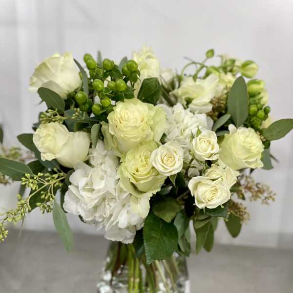 White roses and hydrangeas in a clear glass vase