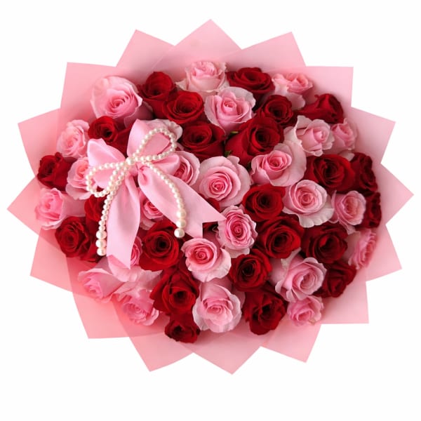 Bouquet of red and pink roses wrapped in pink paper with a pearl bow