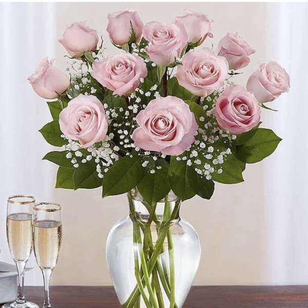 Pink roses arranged in a clear glass vase with baby's breath