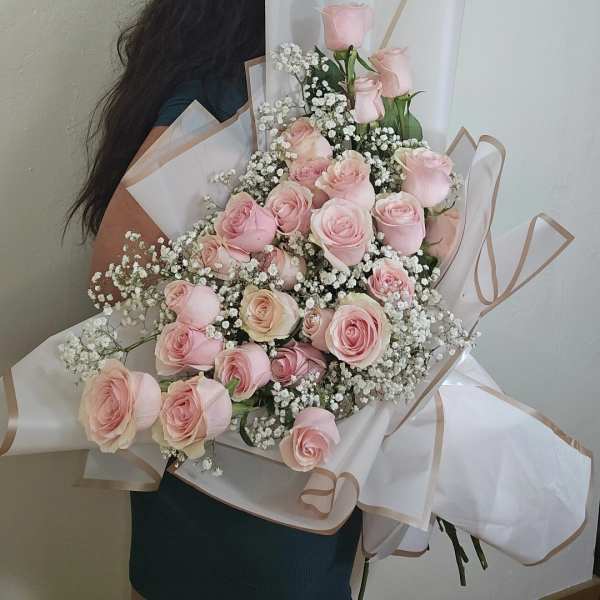 Large bouquet of pale pink roses with white baby's breath in white wrap