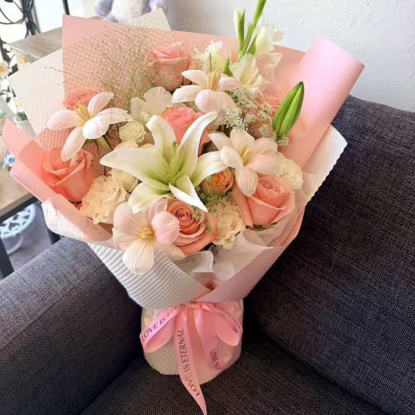 Pink and white bouquet with roses and lilies wrapped in pastel paper