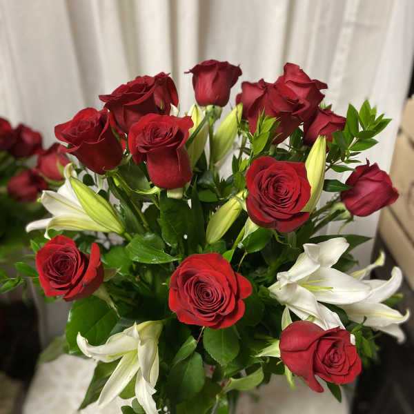 Bouquet of red roses and white lilies with green foliage