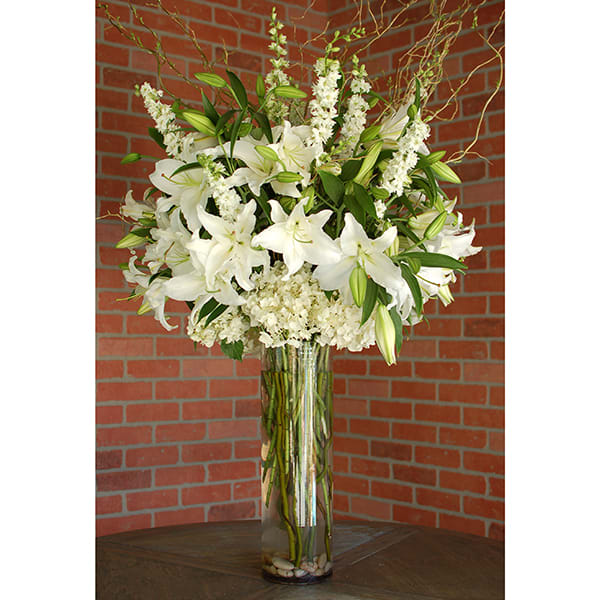 Tall white lily arrangement in a clear glass vase