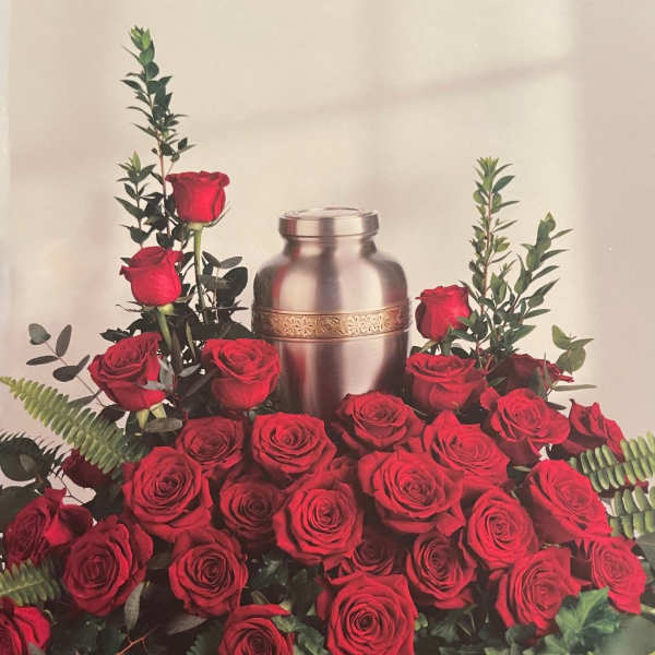 Red roses arranged around a silver urn with greenery