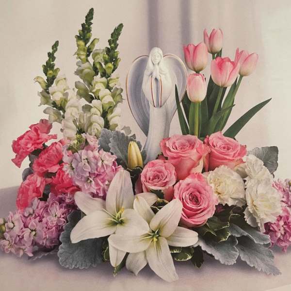 Pink roses, white lilies, and tulips arranged around a figurine