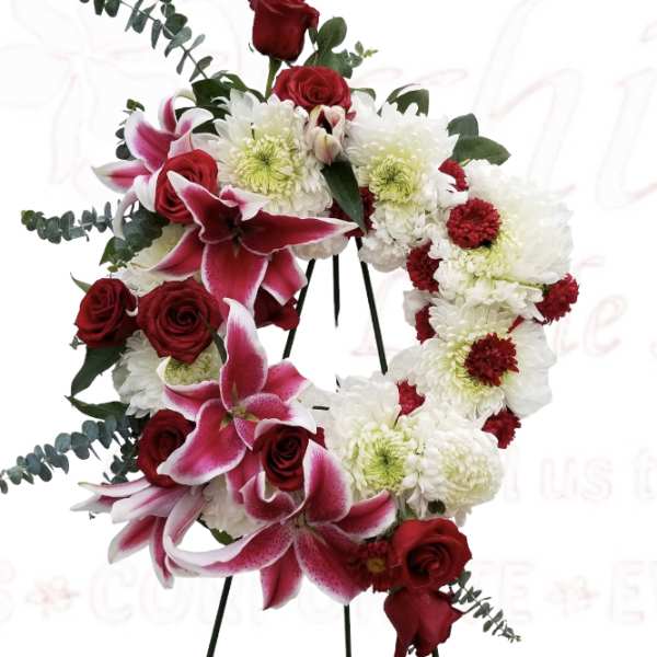 Heart-shaped floral wreath with red roses, pink lilies, and white chrysanthemums