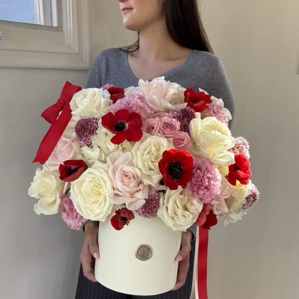 Large bouquet of pink, white, and red flowers in a cream box