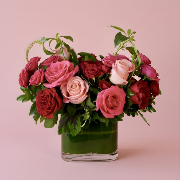 Bouquet of pink and red roses in a green glass vase