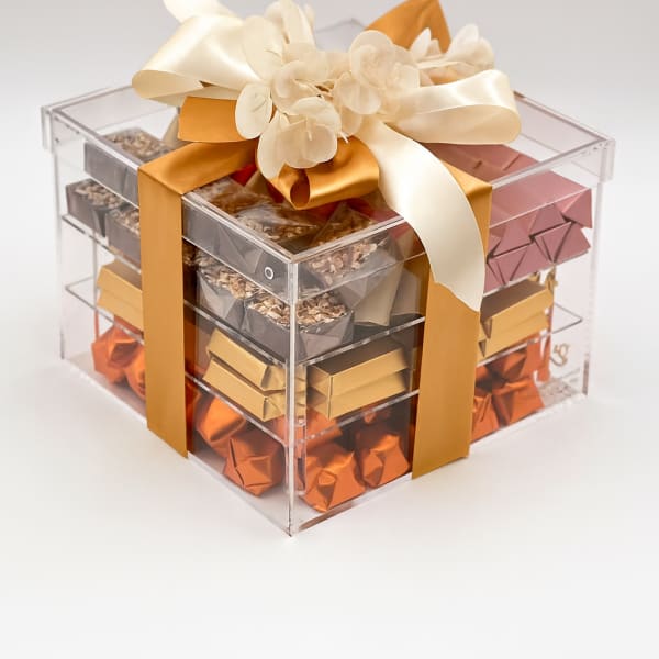Clear gift box filled with assorted chocolates and topped with a cream ribbon bow