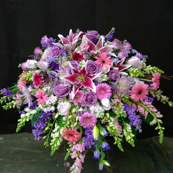 Large standing spray of pink, purple, and white flowers on a tripod easel