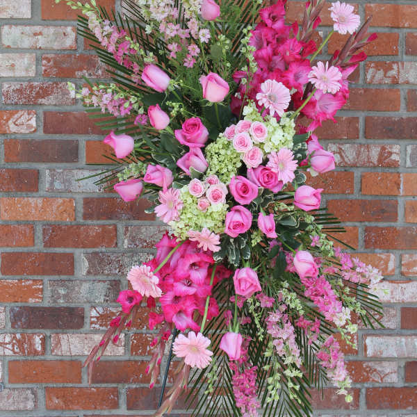 Tall pink standing spray with roses and mixed flowers on a metal easel